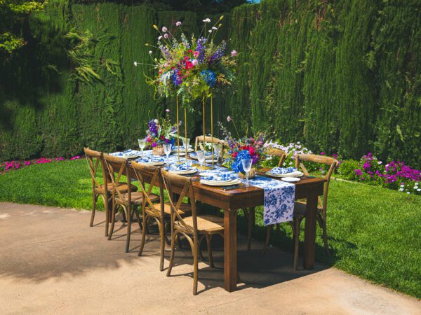 Wooden table with decor before vibrant green hedges