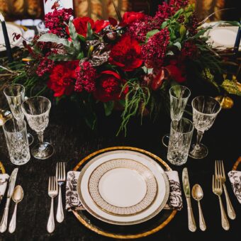Table setting with white plates, napkins, silverware, and red flowers