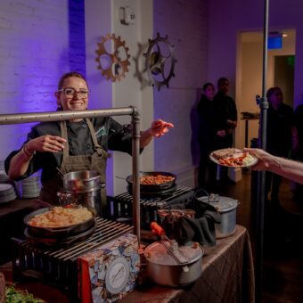 smashing dishes employee standing behind a table of dishes and handing someone a plate of food