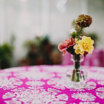 vase of flowers on top of patterned pink tablecloth
