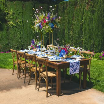 rectangle table in garden set with blue floral table cloth and flower arrangements